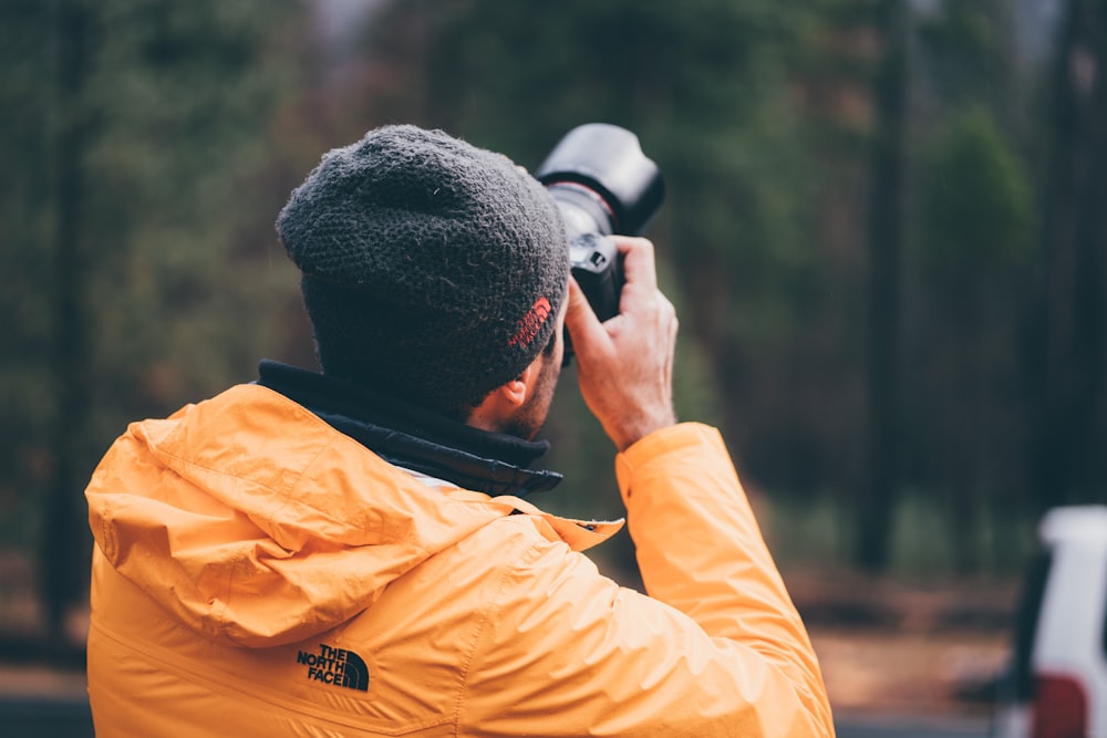 hombre sosteniendo una cámara DSLR negra