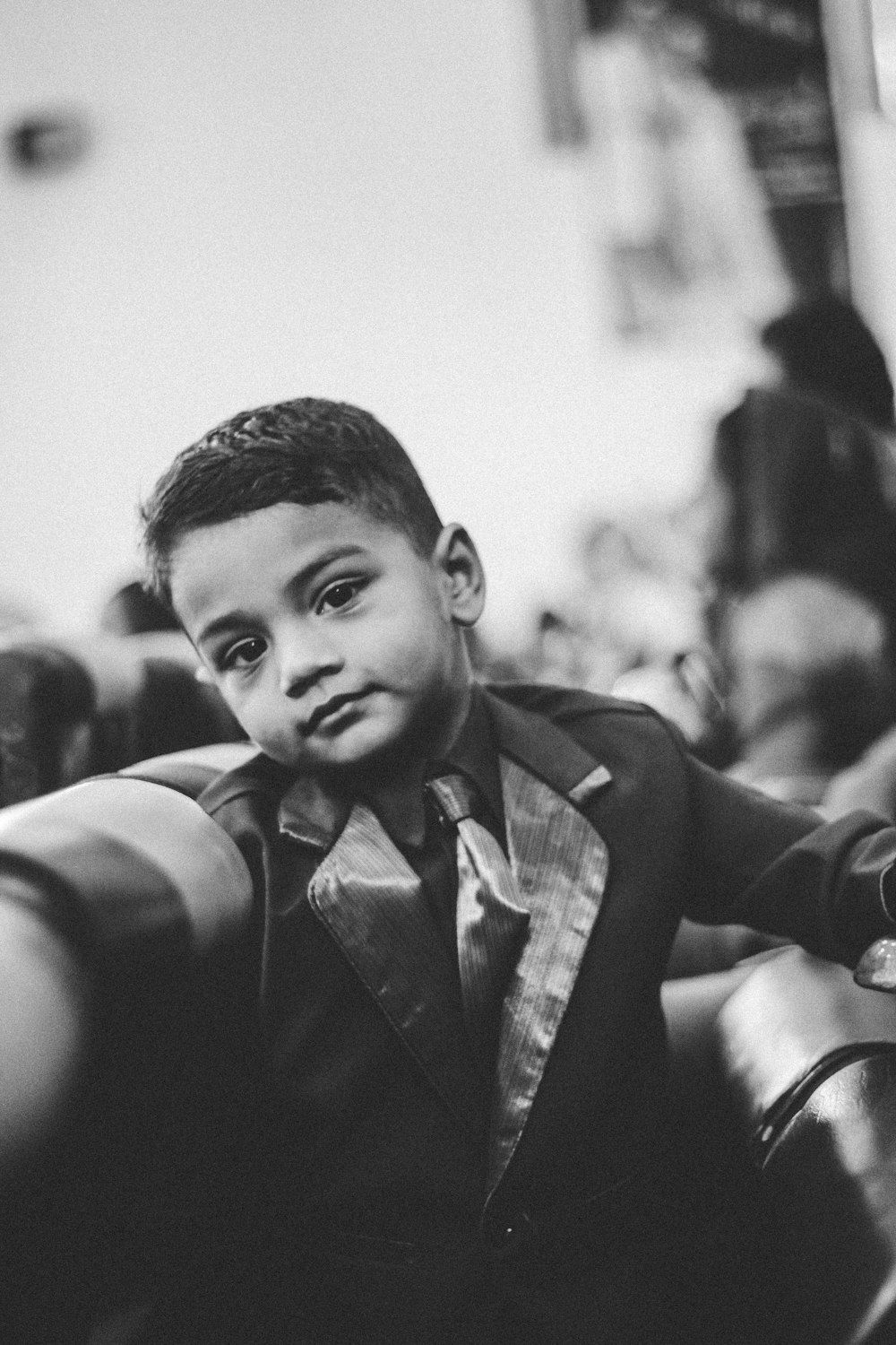 grayscale photography of smiling boy in formal suit jacket