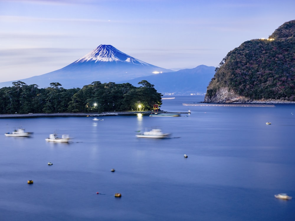 white boats in body of water in front of mountain