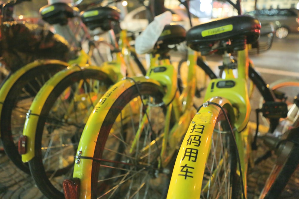 quatro bicicletas amarelas estacionadas ao lado da estrada