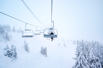 person riding cable train above snow covered field