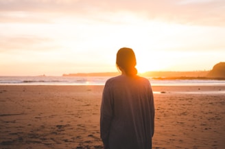 woman standing on sand and facing at seashore