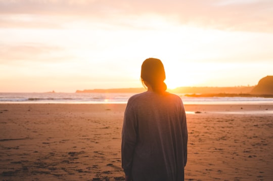 woman standing on sand and facing at seashore in Smiths Beach Australia