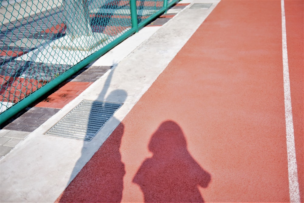 two person's shadow on brown and red surface