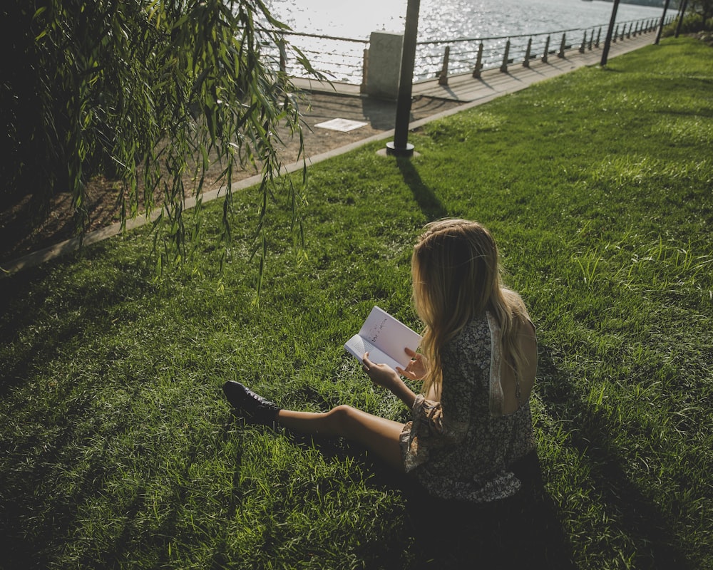 woman reading book sitting on field