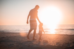 man holding girl heading towards sea