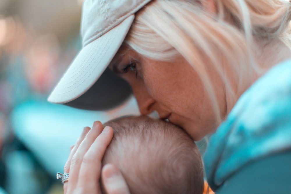 macro photography of woman kissing baby head