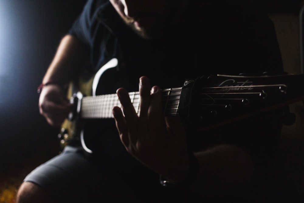 low light photography of man playing guitar