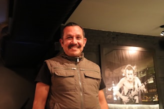A warm photo of Cantor Ed Nascimento holding a guitar and smiling warmly.