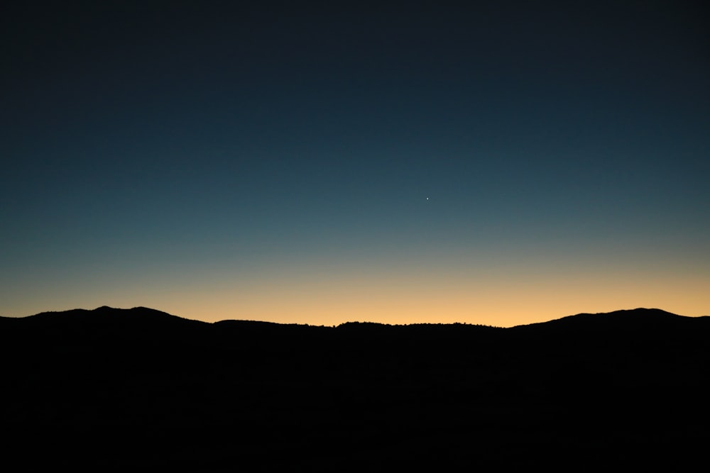 the sun is setting over a mountain range