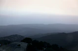 A minimalist landscape with soft morning fog over rolling hills.