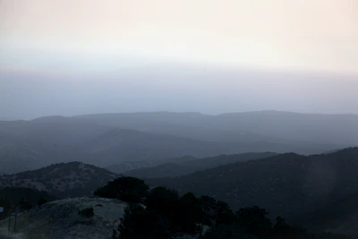 A minimalist landscape with soft morning fog over rolling hills.