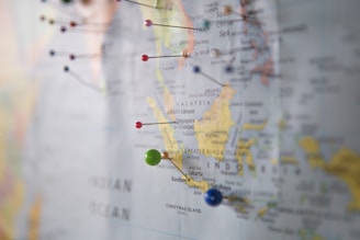 A close-up of a map featuring South East Asia, with colorful pins marking various locations such as Malaysia, Singapore, and Indonesia. The focus is on the area around the South China Sea and Indian Ocean, with cities like Kuala Lumpur and Jakarta visible.
