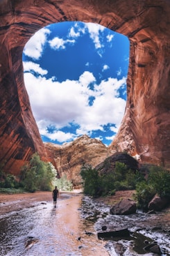 man walking under cave during daytime