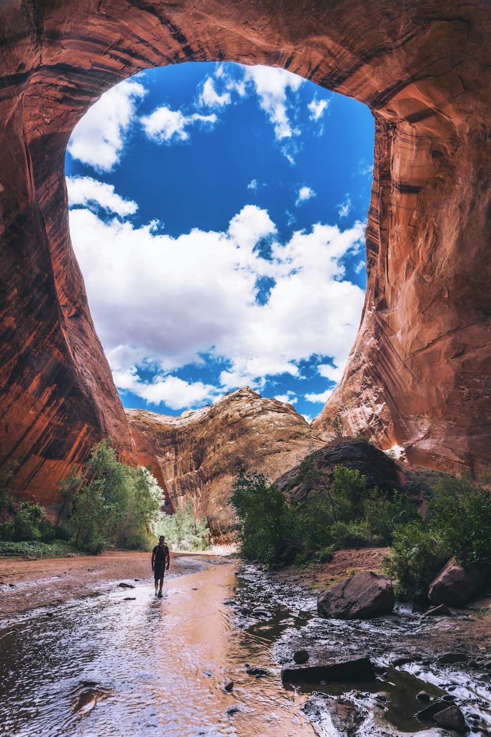 man walking under cave during daytime