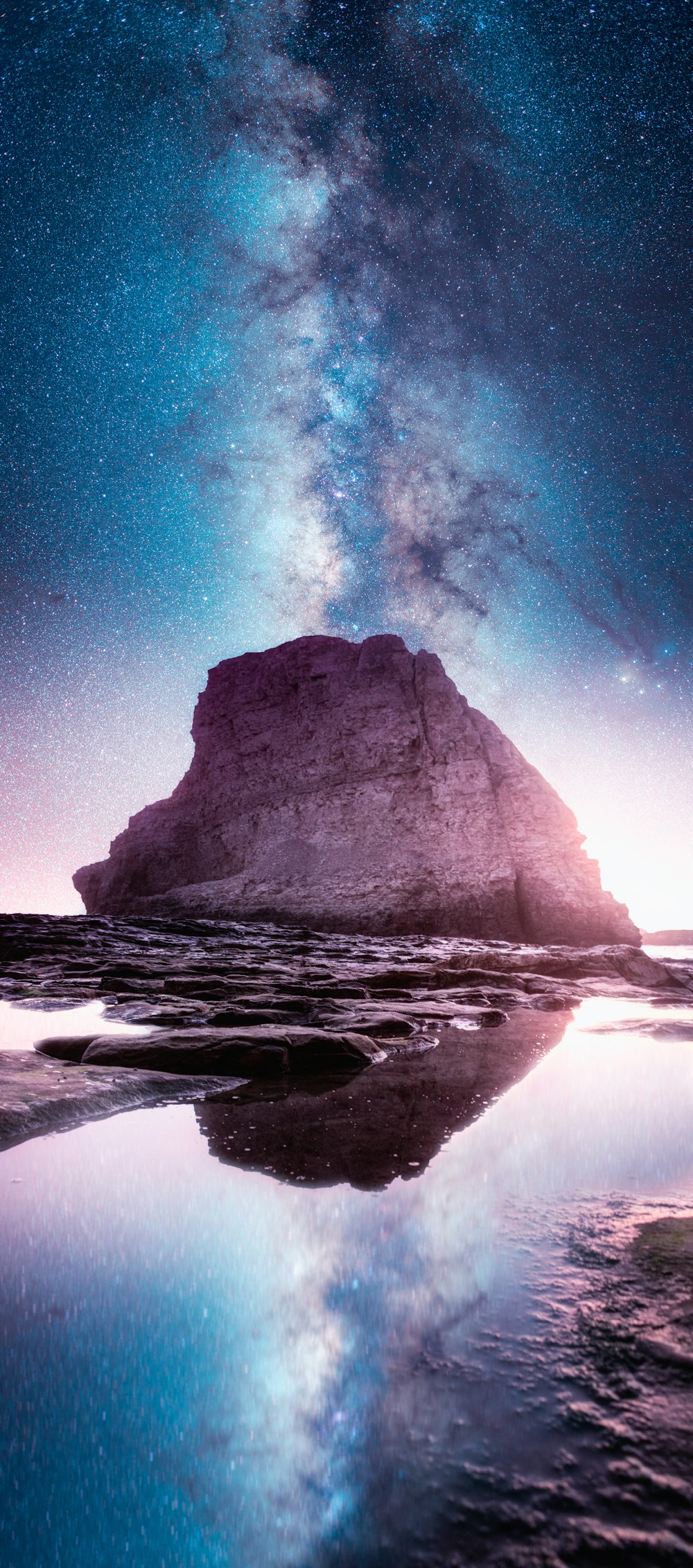 landscape photography of body of water near rock mountain under stargazer