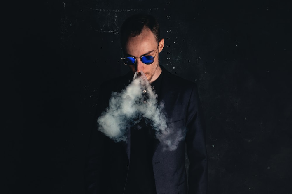 homem na jaqueta preta do terno fumando