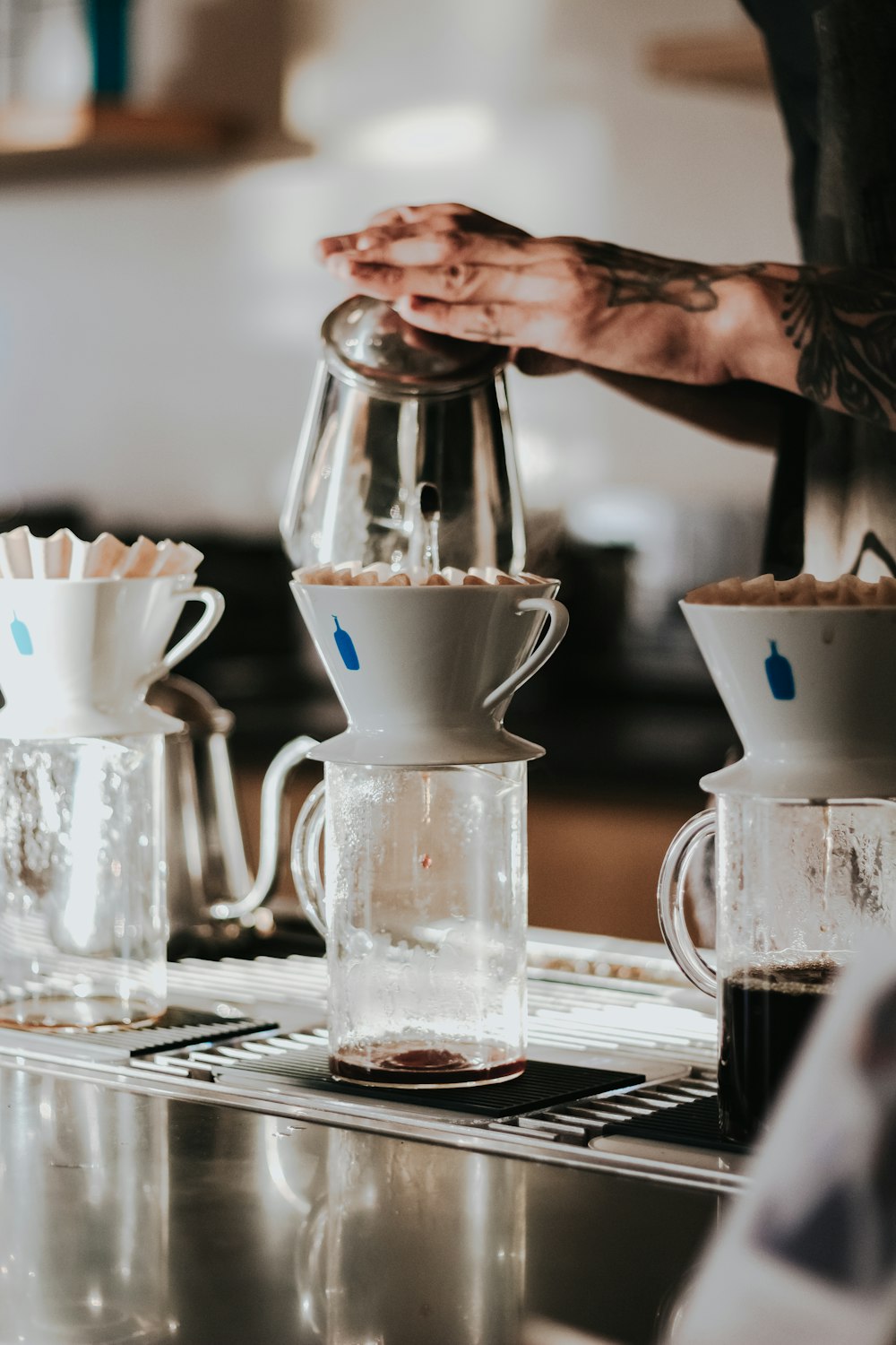 person holding filling white cup over glass container