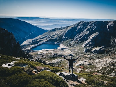 man standing on top of rock facing mountain