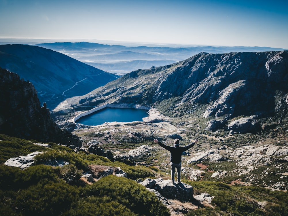 man standing on top of rock facing mountain