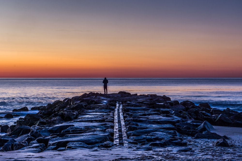 person standing on rocks silhouette