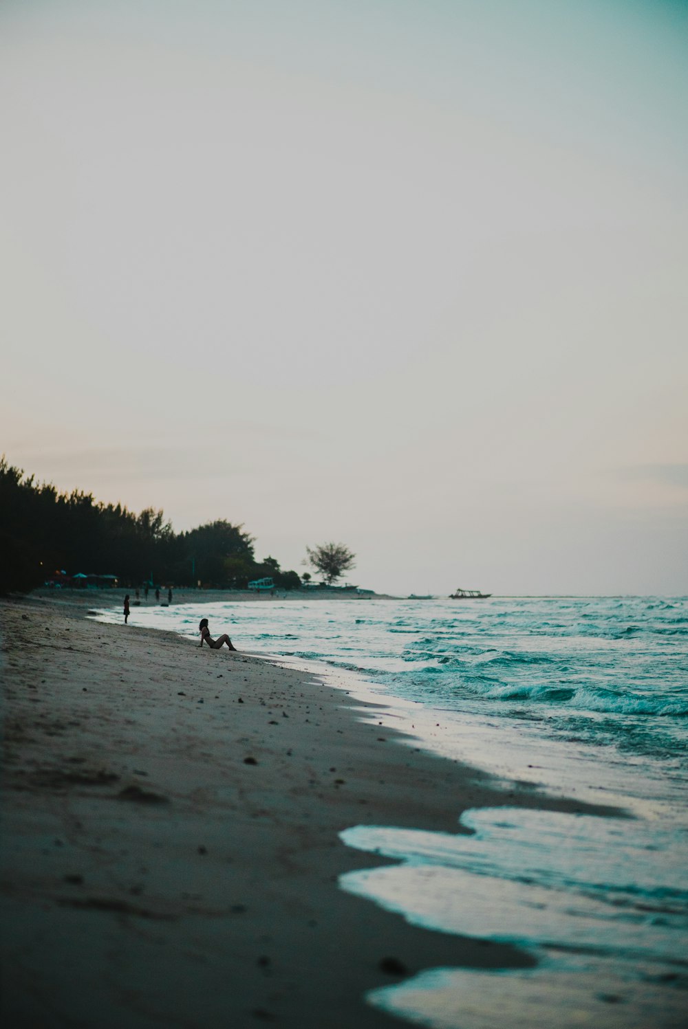 person sitting on shore looking at waves