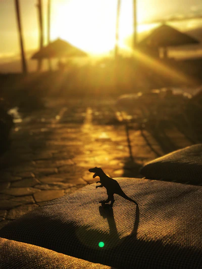 A fierce dinosaur from Beast of Bermuda roaring on a rocky shore at sunset.