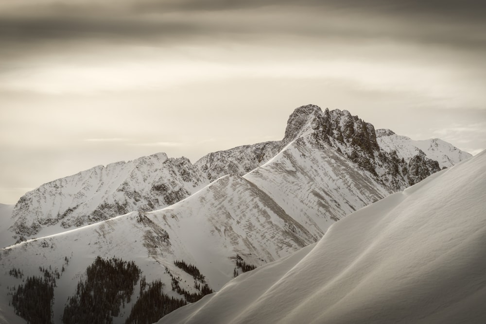 snow-covered mountains under gray clouds during daytime