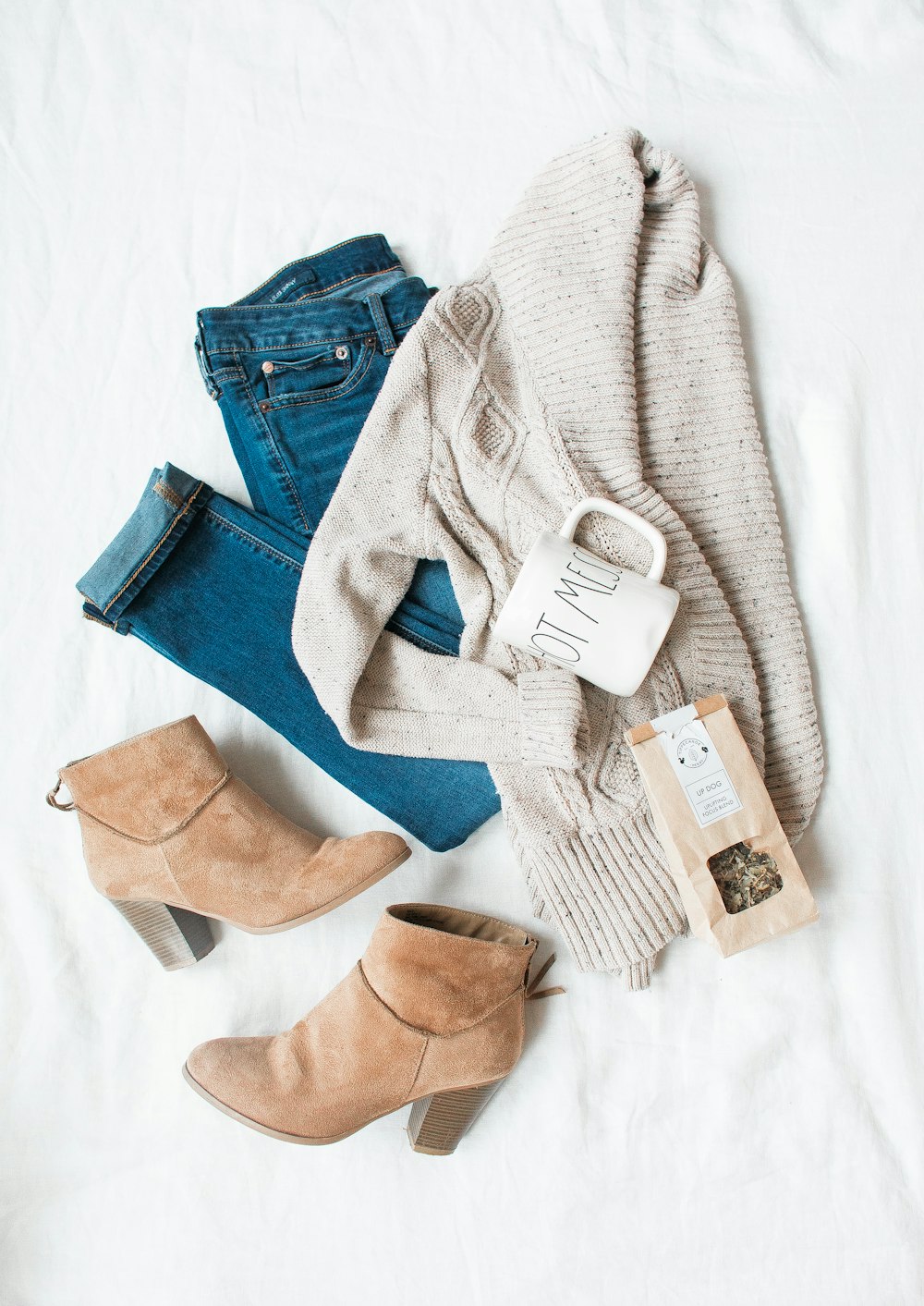 graue Strickjacke, blaue Jeans und ein Paar braune Schuhe mit klobigen Absätzen