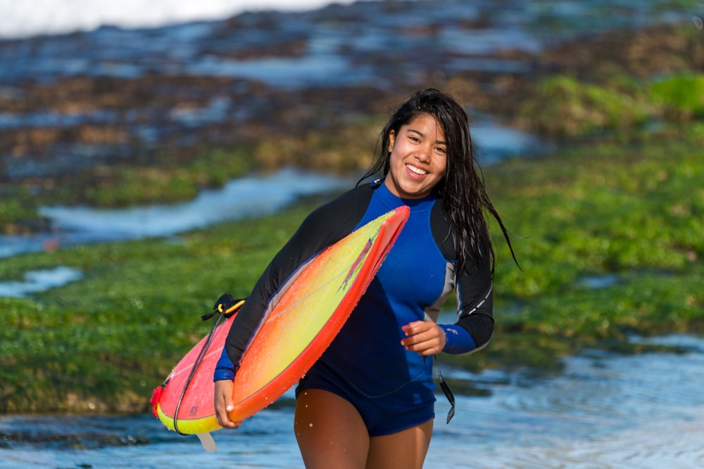 Mujer sonriente que lleva la tabla de surf durante el día