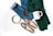 A neatly arranged flat lay featuring a pair of jeans, a green knitted sweater, a pair of patterned loafers, a metal belt, a mug labeled 'COFFEE', and a bowl of coffee beans. The items are placed on a white background, indicating a casual, cozy theme.