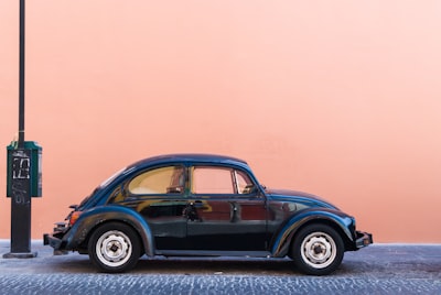 black Volkswagen Beetle beside beige wall