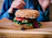 Close-up of a vibrant Thai sandwich with fresh herbs and colorful vegetables.
