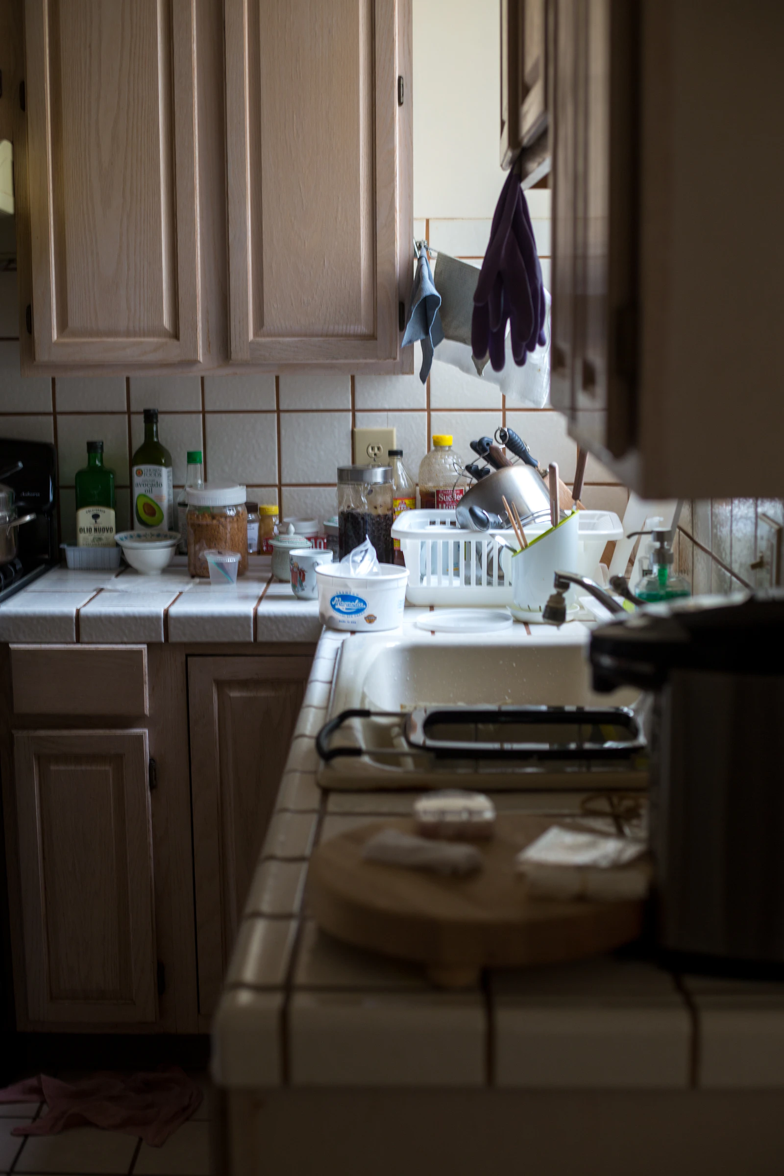 Cluttered, worn-down kitchen with dated cabinets and messy counters before renovation