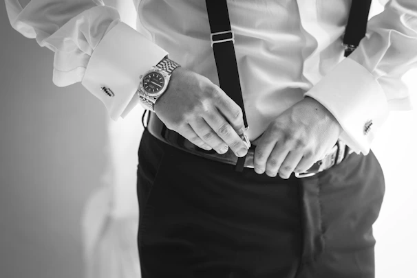 A cinematic shot of a groom adjusting his cufflinks in a vintage mirror.