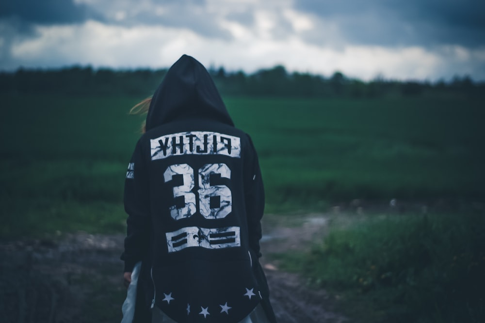 person wearing hooded jacket staring at grass
