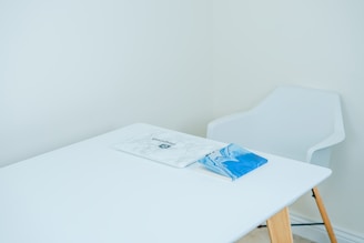 blue covered book on white table with armchair in front