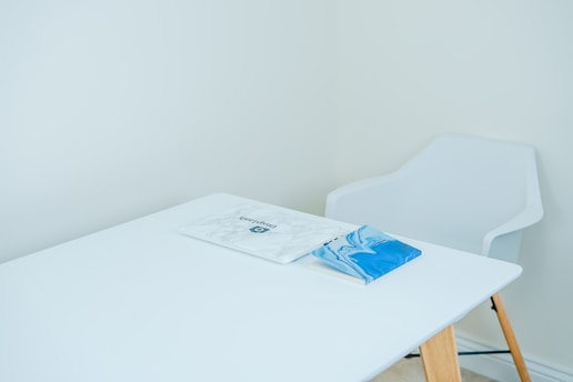 blue covered book on white table with armchair in front