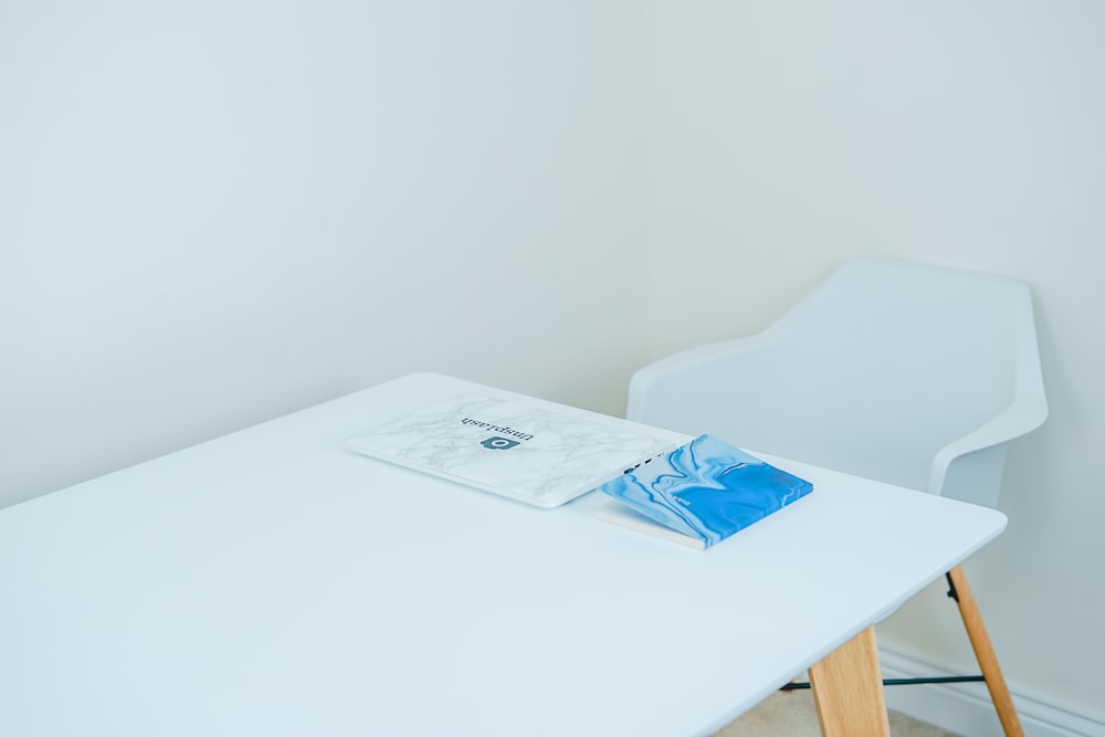 Libro de tapa azul sobre mesa blanca con sillón al frente