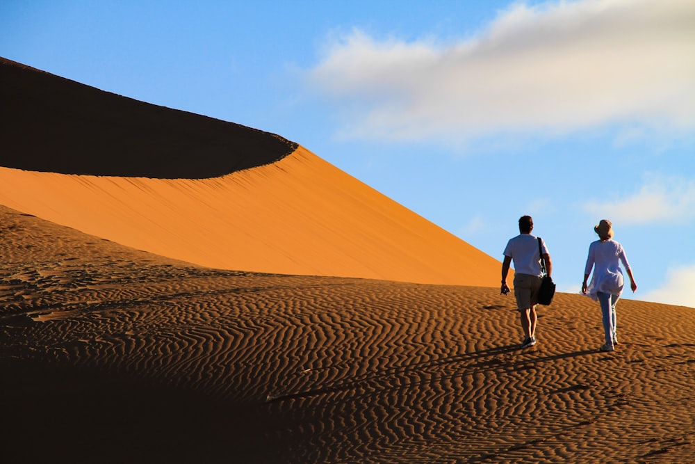 man and woman walking on desert