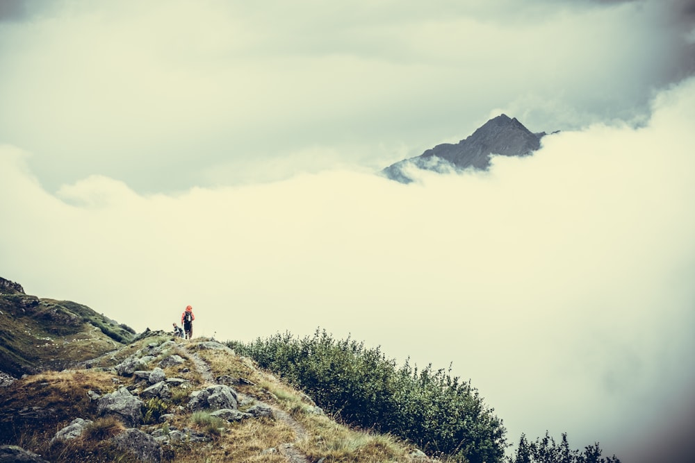 person on cliff watching sea of clouds