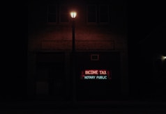 A dimly lit street scene at night features a brick building with a neon sign displaying the words 'INCOME TAX' in red and 'NOTARY PUBLIC' in green. A streetlight illuminates the space immediately around it, creating a contrast with the dark surroundings.