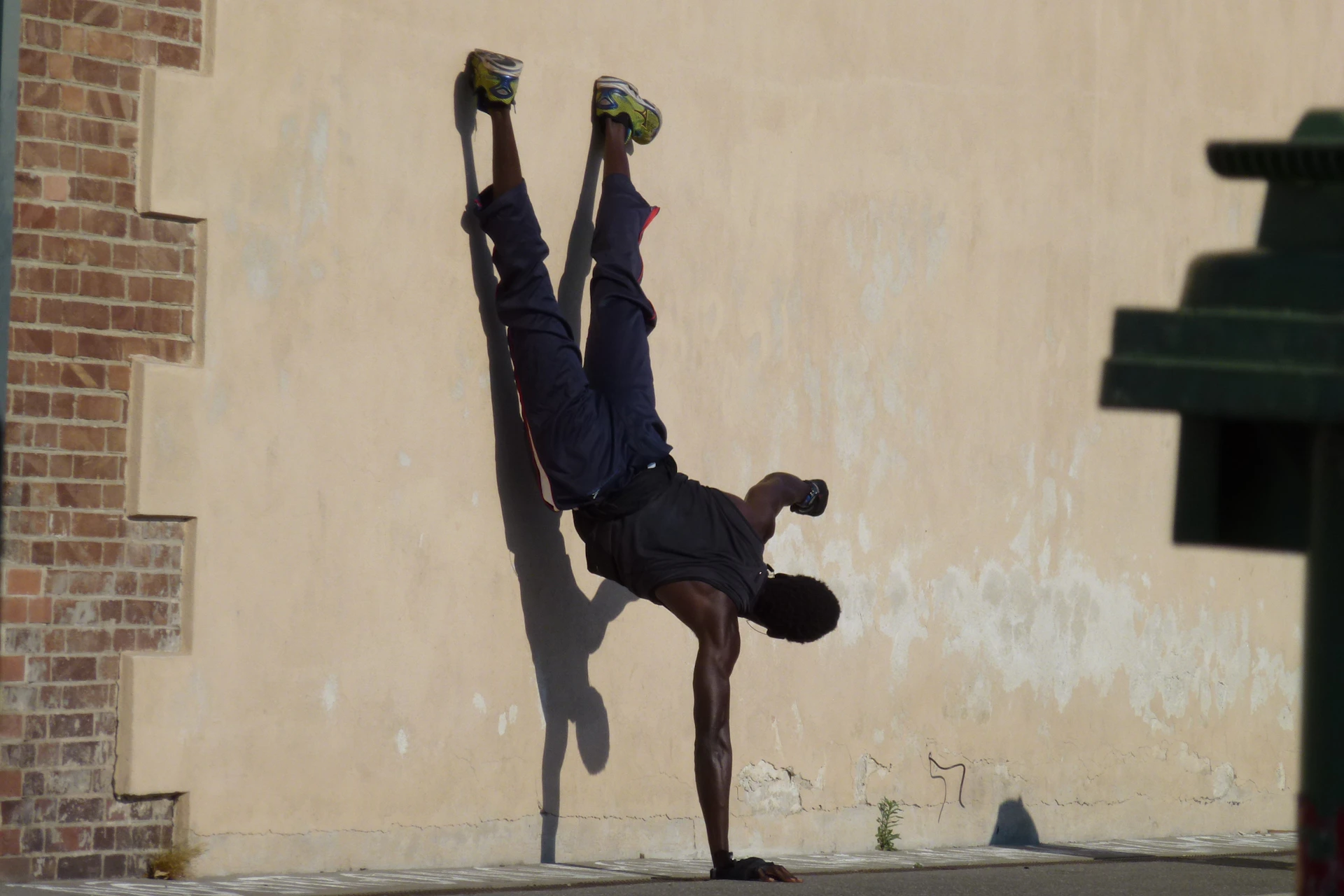 A focused handstand pose in an urban setting with clean lines and subtle shadows emphasizing strength and balance.