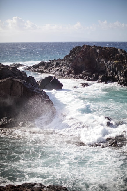 Waves crashing against the cliffs of the Algarve coastline on a sunny day