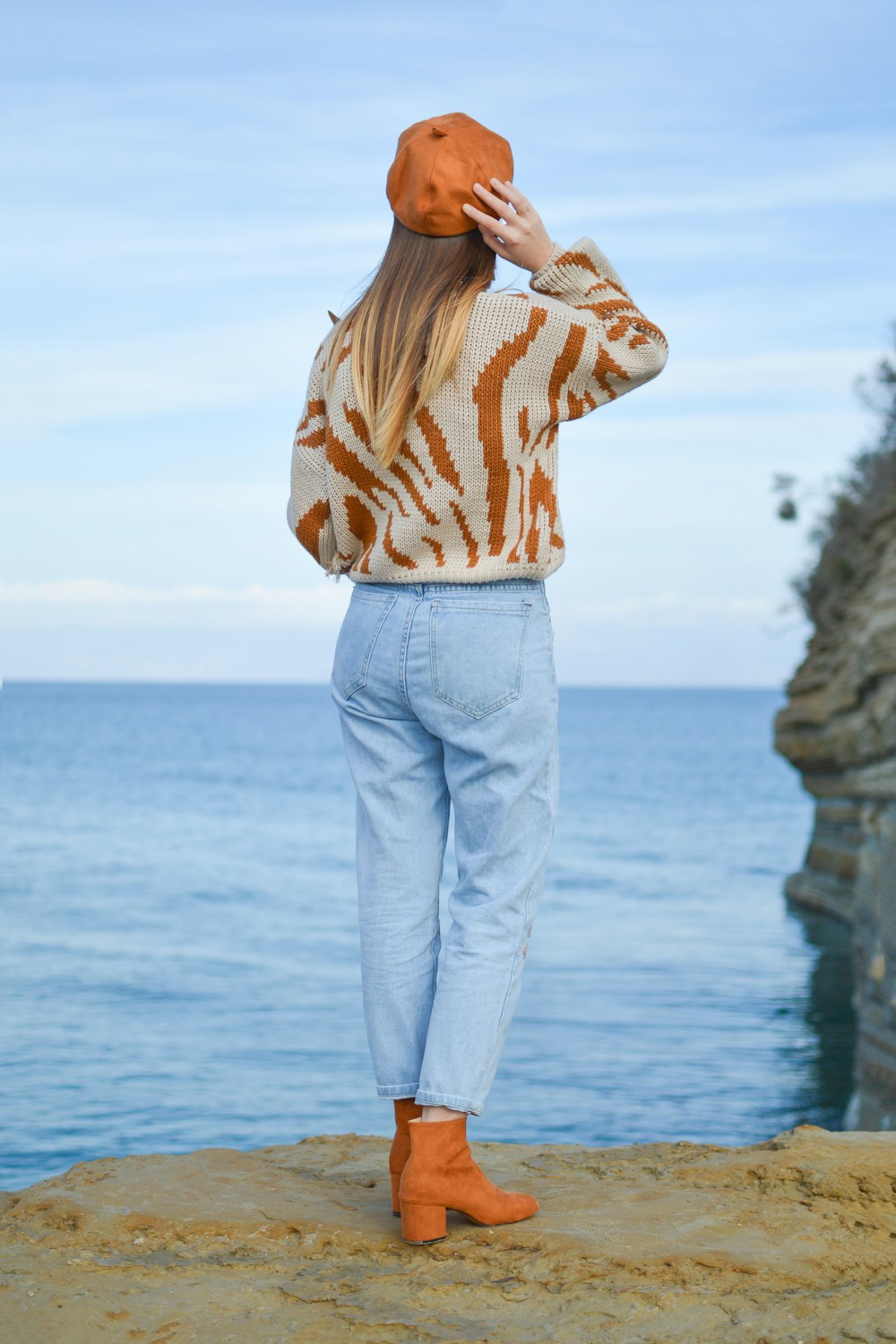 woman standing on cliff staring at horizon