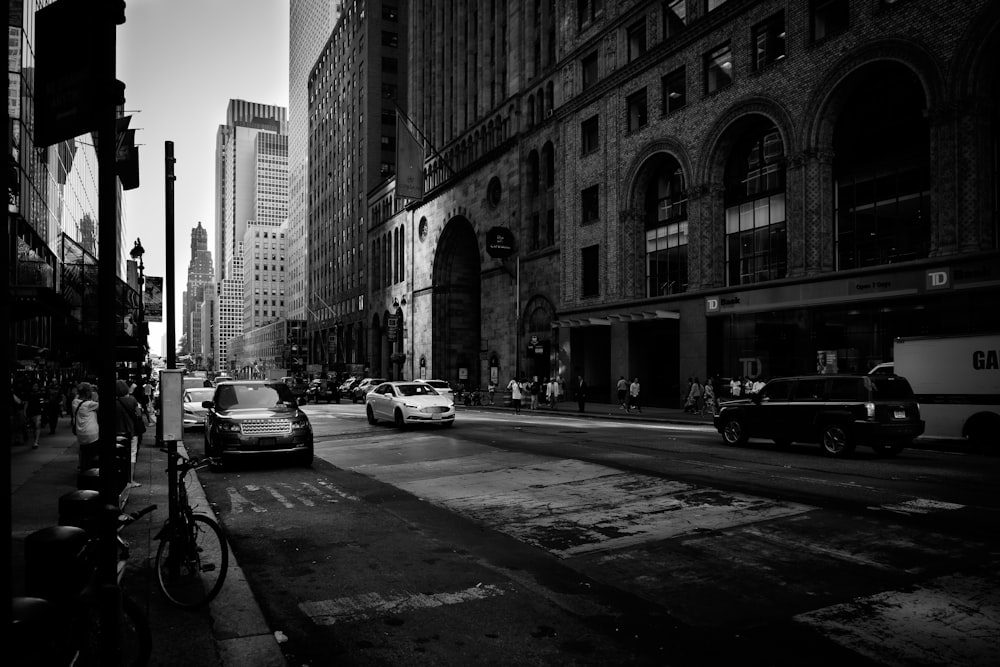 grayscale photo of cars near building