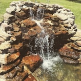 Close-up of natural stone waterfall flowing into a clear pond.