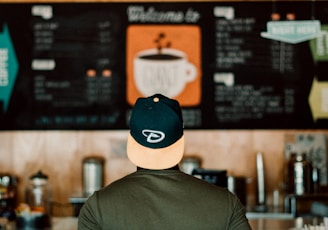 photo of person wearing cap staring at menu board