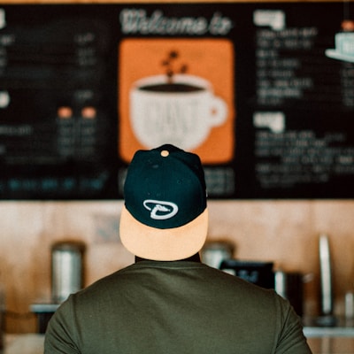 photo of person wearing cap staring at menu board