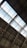The image captures the interior view of a large industrial or warehouse building with a high ceiling. The roof structure is made up of metal beams and girders, with large glass panels letting in natural light. The overall architecture appears sturdy and functional.